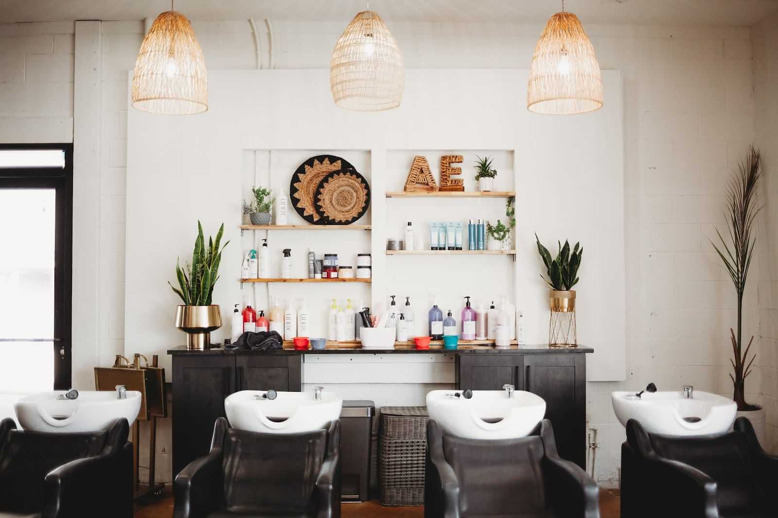 Modern hair salon with stylish decor, three hair washing stations, and various hair products.