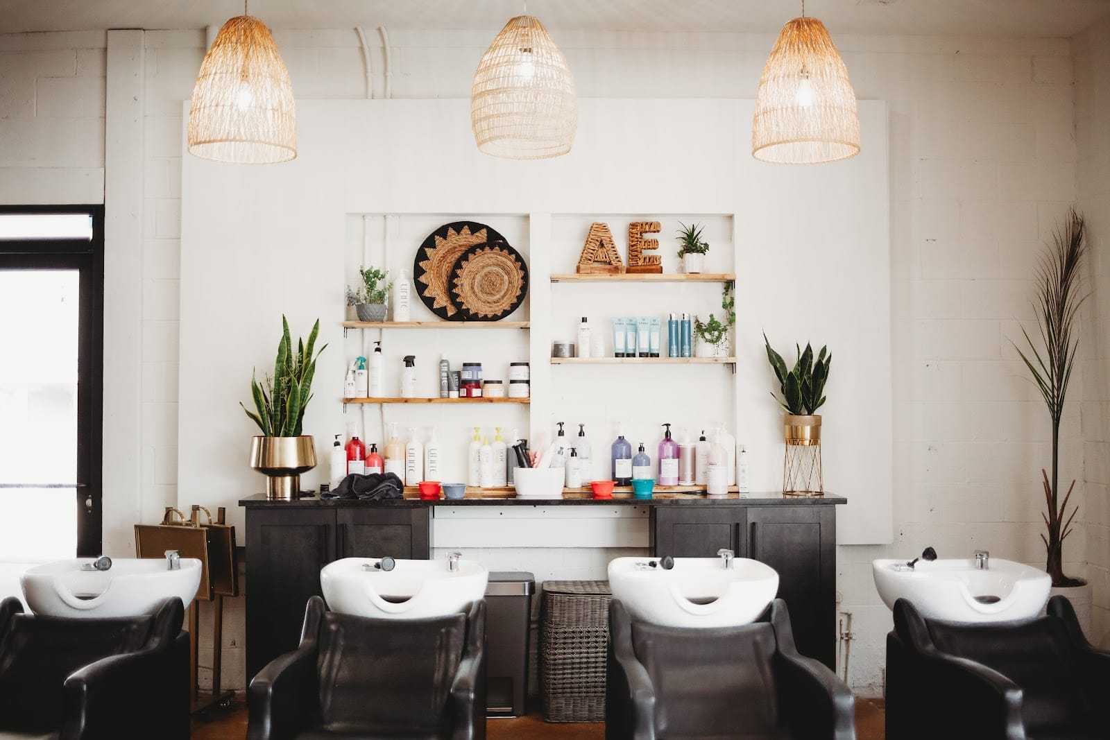 Modern hair salon with stylish decor, three hair washing stations, and various hair products.